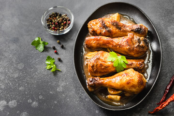 Honey mustard chicken legs in cast iron skillet on dark background. Top view, copy space.
