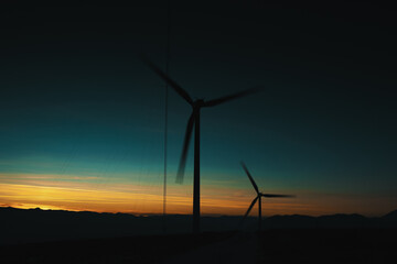 Fototapeta premium A wind farm or wind park at sunset located in the mountains of Italy Europe and it allows to realize clean energy. It’s sustainable, renewable energy for enviromental