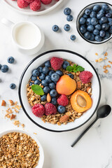 Breakfast granola bowl with berries, fruits and almond milk in a jug. Top view. Dieting, healthy eating concept