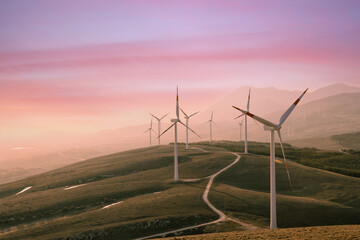 A wind farm or wind park at sunset located in the mountains of Italy Europe and it allows to...