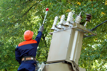 The electrician installs the ground on the power line before repairing the substation