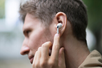 close up male person using wireless earphones and listen to the music