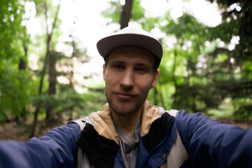 male bearded person traveling and hiking, taking selfie in the forest