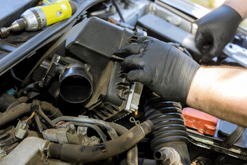 Fototapeta na wymiar Mechanic hand is replacement car air filter into car engine in service center