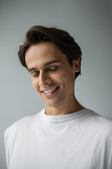 portrait of happy man in white t-shirt smiling isolated on grey
