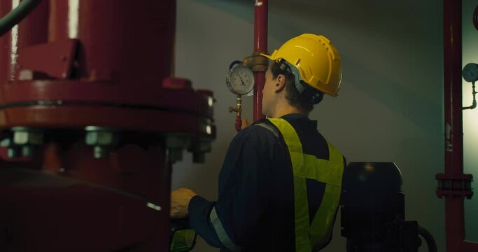 Professional engineer worker man in safety uniform holding flashlight checking maintenance the industry pipeline pump system construction under the building factory