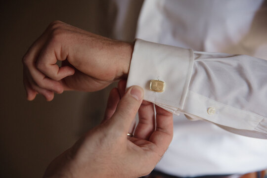 Close-up of a groom fastening his cufflinks, preparing for his wedding day.