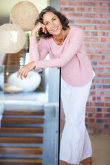 Enjoying the comforts of home. Full length portrait of a mature woman leaning on a glass railing.