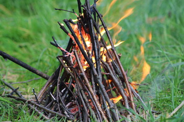 Bonfire in the forest. Bonfire lit at A picnic in a forest. Green grass, trees and a soccer ball in the background
