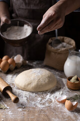 Fototapeta premium Baker chef man sprinkling flour at dough bread and bakery ingredients for homemade cooking on table