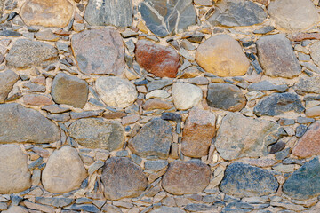 Granite wall made of natural stone. Seamless texture. small and large stones