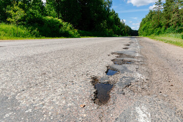 Poor quality road with potholes. Holes in the roadway. Risk of driving.