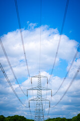 Pylon Power Electricity Electrical Distribution Aerial Cable Running through Countryside Farmer Fields with Blue Sky and White Clouds