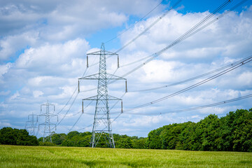 Pylon Power Electricity Electrical Distribution Aerial Cable Running through Countryside Farmer Fields with Blue Sky and White Clouds