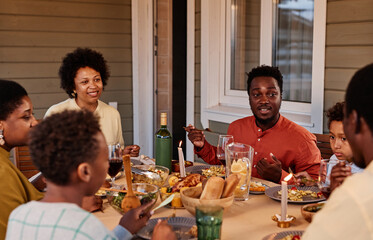Portrait of smiling African American woman enjoying dinner with family on terrace outdoors
