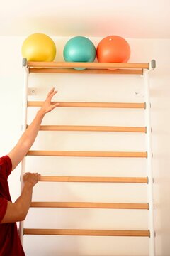 Vertical Shot Of A Person Reaching For The Balls On The Top Shelf Of The Wooden Stairs For Gymnastic