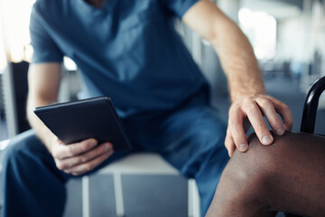 Close-up of doctor using digital tablet while examining pain leg of patient