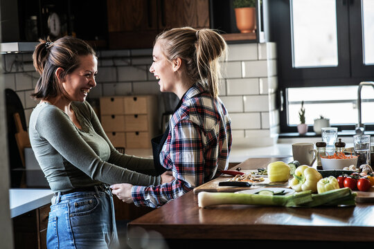 LGBT Lesbian couple preparing meal at home.They are showing affection to each other.	
