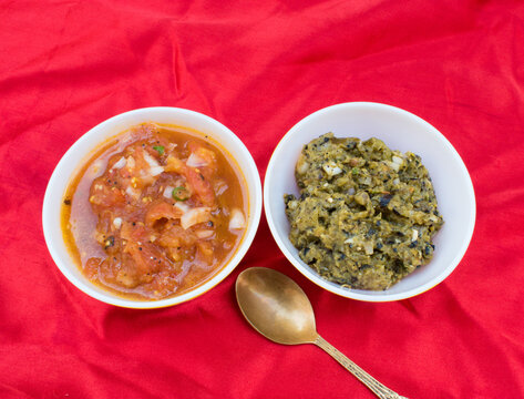 Salted Tomato chutney dip or salsa with roasted tomato, onion, green chilli and parwal or pointed gaurd chutney in white bowl and red background. No oil and healthy dressing for salad.