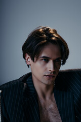 stylish man in striped jacket and hairy chest looking away on dark grey background