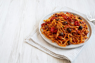 Homemade Tuna Linguine Pasta with Tomatoes, Olives and Capers on a Plate, low angle view. Copy space.