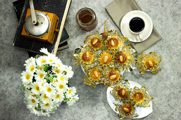 Oriental Algerian sweet cookies named dziriettes in Arabic language with manual coffee grinder and honey jar, daisy flowers 
