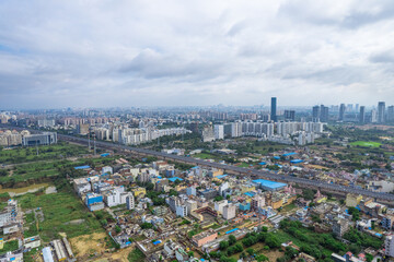 Fototapeta na wymiar aerial drone shot over gurgaon showing monsoon clouds with light rays falling on ground crowded with homes houses, sohna highway feilds and water pools around under construction buildings