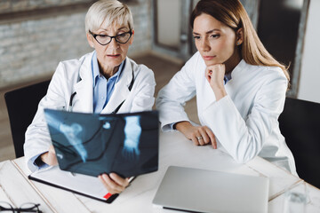 Two medical experts examining an X-ray image in the office