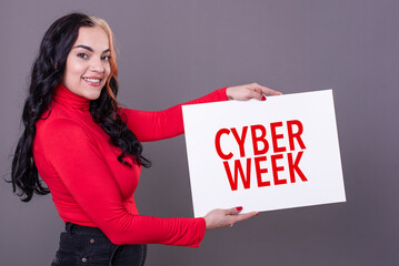 Beautiful woman holding a Cyber Week sign against a grey background