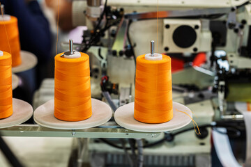 Spools with orange threads on sewing machine. Sewing Equipment, Textile Industry