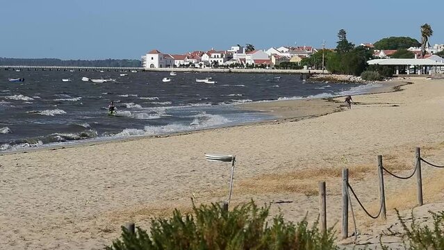 Man kitesurfing on Moinhos beach in Alcochete, Portugal with a clear sky and resort view background