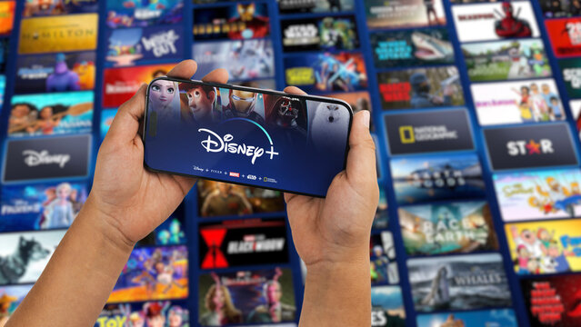 Boy holding a smartphone iPhone 14 Pro with Disney+ (Disney Plus) streaming app app on the screen. Website blurred in the background. Rio de Janeiro, RJ, Brazil. October 2022