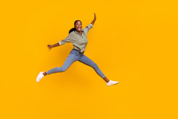 Full length photo of satisfied person jumping raise hands open mouth isolated on yellow color background