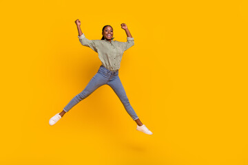 Fototapeta na wymiar Full length photo of excited astonished lady jumping raise fists luck isolated on yellow color background