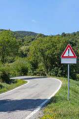 Mountain road with warning sign, Toscano Emiliano Park in Parma province, Italy