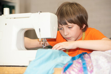handsome boy sewing clothes on a sewing machine at home