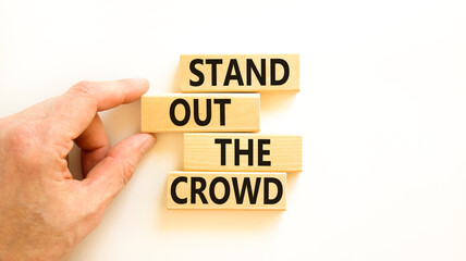 Stand out the crowd symbol. Concept words Stand out the crowd on wooden blocks on beautiful white table white background. Businessman hand. Business, stand out the crowd concept