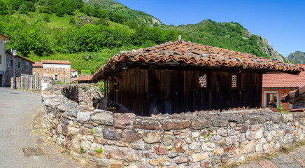 Casa rural de pueblo solitaria rodeada de un muro de piedra, en un paisaje rural de montañas verdes, en la zona de Somiedo, Asturias, rodeado de naturaleza en España, verano de 2021