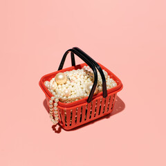 Shopping basket idea, elegant pearls and earrings, pastel pink background. 