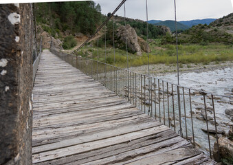 Fototapeta premium a stone pier, cable stay suspension foot bridge over a mountain river 
