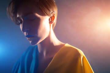 young ukrainian woman in yellow and blue clothes and dress praying for ukraine