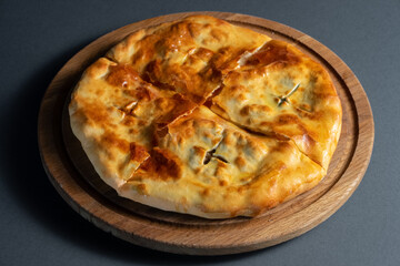 traditional georgian bread khachapuri on wooden board on black background