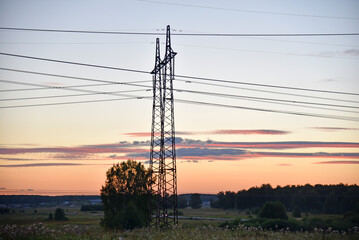 Fototapeta premium Beautiful high-voltage iron transmission line in the evening in the sunset sky. Landscape evening and wires and power lines.