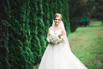 Obraz na płótnie Canvas Luxury wedding bride, girl posing and smiling with bouquet