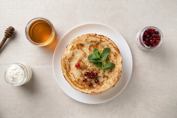 Stack of homemade pancakes served with honey and berries, top view