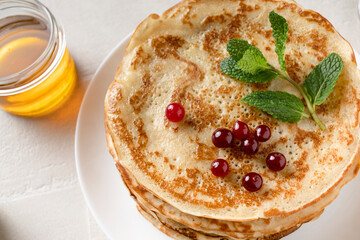 Stack of homemade pancakes served with honey and berries, top view