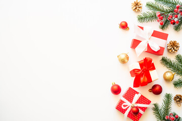 Christmas holiday decorations at white background with copy space. Gift boxes, fir tree, baubles and others. Flat lay composition.