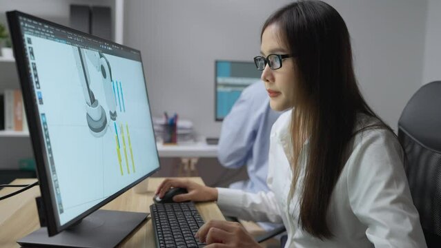 Young asian woman design robot arm in her office. Concentrated woman creating her own project, She creating prototype robot hand model by 3d animation software.