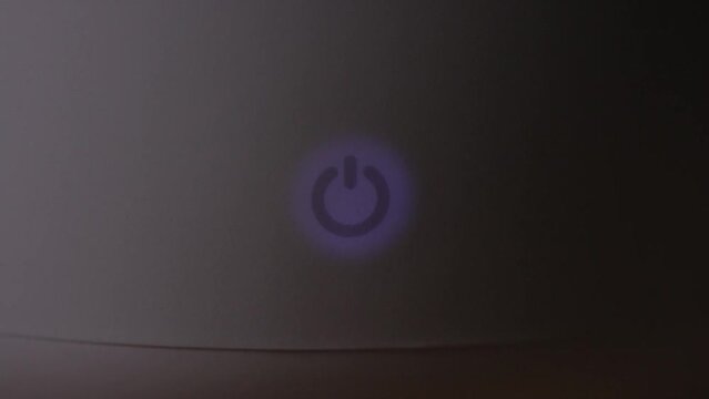 Finger Turning On A Power Button As It Continues To Glow