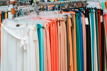 An assortment of multi-colored women pants made of light and trendy material and fabric on a hanger for sale in a clothing store